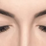 Close-up of closed eyes with thick lashes and defined brows after LATISSE eyelash treatment in Gilbert, AZ.
